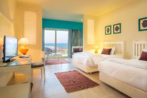 Cette chambre comprend deux lits et une télévision. dans l'établissement Caesar Bay Resort, à Marsa Matruh