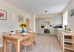 a kitchen with a wooden table and chairs and a kitchen with white cabinets at 1 Redsteads 