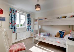 a childs bedroom with two bunk beds and a window at Mayflower Cottage in Seahouses