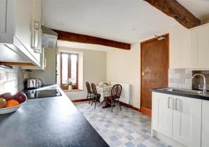 una cucina con armadi bianchi e tavolo con sedie di Oxnop Cottage a Gunnerside