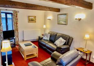 a living room with a leather couch and a table at Oxnop Cottage in Gunnerside