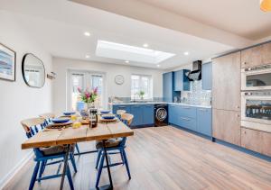 cocina con mesa de madera y armarios azules en Grace Cottage en Amble