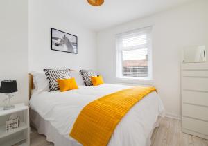 Un dormitorio blanco con una manta amarilla en una cama en Grace Cottage en Amble