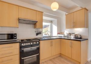 a kitchen with wooden cabinets and a stove top oven at The School House in Kirknewton