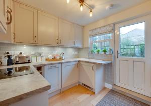 una cocina con armarios blancos y una ventana en Munton Cottage en Crakehall