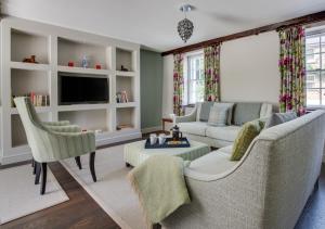 a living room with a couch and chairs and a tv at Memories Cottage in Milnthorpe