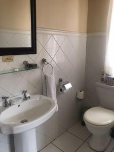 a white bathroom with a sink and a toilet at Brooklyn Place in Pretoria