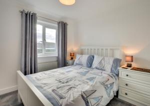 a white bedroom with a bed and a window at Mena-Gwins in Padstow