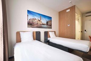 ブリュッセルにあるイージーホテル ブリュッセル シティ センターのベッド2台が備わる客室で、壁には絵画が飾られています。