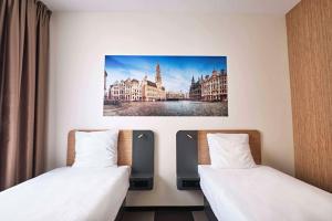 two beds in a hotel room with a picture on the wall at easyHotel Brussels City Centre in Brussels