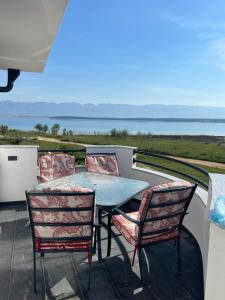 a table and chairs on a balcony with a view of the ocean at Apartments Linic in Nin