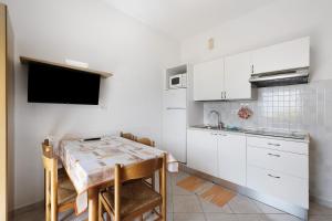 a kitchen with white cabinets and a table with chairs at Numero 14 in Borgio Verezzi +15 photos