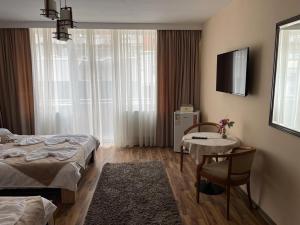 a room with two beds and a table and a television at Casa Alex in Târgu Jiu