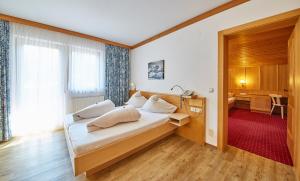 a bedroom with a bed and a desk and a window at Apart-Hotel Forellenhof in Saalbach Hinterglemm