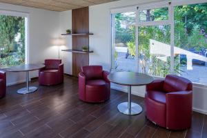 een wachtkamer met rode stoelen, tafels en ramen bij Noemys ARLES in Arles
