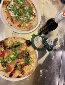 two pizzas on plates on a table with a bottle of wine at Steinerhaus Berggasthof in Gröbming