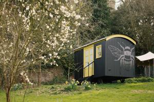 a small train car sitting in a yard with flowers at Beekeeper's Hut - Hawarden Estate in Hawarden