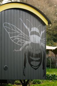 Beekeeper's Hut - Hawarden Estate في Hawarden: لوحة نحلة على جانب المبنى
