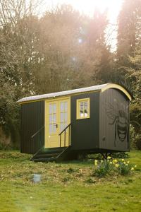 um pequeno barracão com uma porta amarela num campo em Beekeeper's Hut - Hawarden Estate em Hawarden