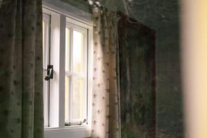 ventana en una habitación con cortina en Beekeeper's Hut - Hawarden Estate, en Hawarden