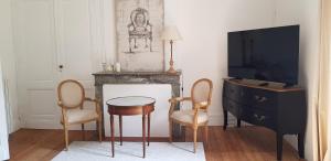 a living room with a tv and a table and chairs at Domaine et Manoir du Picaud in Monestier