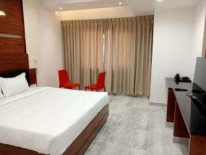 a bedroom with a bed and two red chairs at HOTELJURA in Rājahmundry