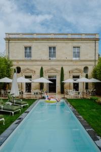 a person swimming in a pool in front of a building at Hôtel Maison Pavlov in Le Bouscat