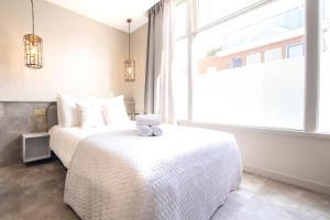 - une chambre avec un lit blanc et une grande fenêtre dans l'établissement Newly Build Utopia City Penthouse 7-Minutes from Rotterdam CS app3, à Schiedam