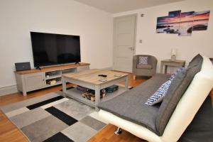 a living room with a couch and a flat screen tv at St James Apartment in Ilfracombe