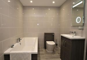 a bathroom with a sink and a tub and a toilet at St James Apartment in Ilfracombe