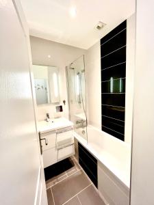 een witte badkamer met een wastafel en een douche bij Ma Location Sablaise - Appart' Grande Plage in Les Sables-dʼOlonne