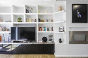 a living room with a tv and white shelves at Villa Miarritze - Welkeys in Biarritz