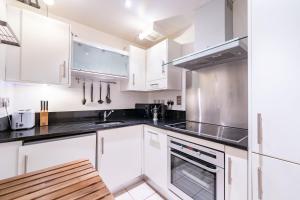 una cocina blanca con armarios y electrodomésticos blancos en Prince William Apartment en Londres