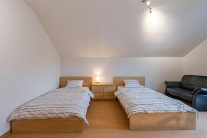 two beds in a room with a couch at Guesthouse in the heart of the flemish ardennes in Zwalm