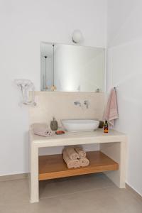 a bathroom with a sink and a mirror and towels at Ihthioessa Boutique Hotel in Astypalaia