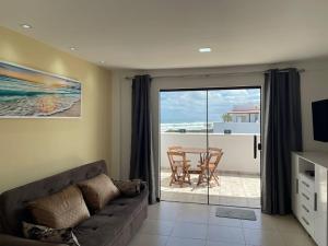 een woonkamer met een bank en uitzicht op de oceaan bij Cobertura Maison dos Colibris in Arraial do Cabo