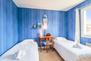 1 dormitorio con 2 camas y escritorio con tabla de surf en la pared en Villa Saint-Georges - Welkeys, en Saint-Georges-dʼOléron