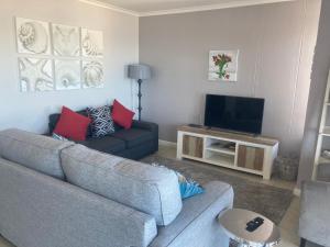 a living room with a couch and a television at Portico 606 in Bloubergstrand