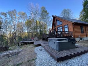 a log cabin with a deck and picnic tables at Joy's Chalet - Hottub, Lake, & Cottage in Val-des-Bois