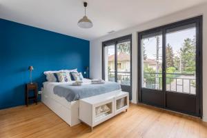 um quarto azul com uma cama e uma grande janela em Familial villa with pool - Tassin-la-Demi-Lune - Welkeys em Tassin-la-Demi-Lune