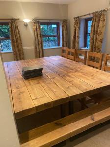 a wooden table in a dining room with chairs and windows at Devonshire -Sleeps 19 in 7 ensuite bedrooms great space for all groups in Peak Forest