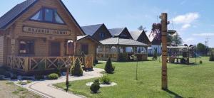 a log cabin with a playground in the yard at Rajskie Domki in Gąski