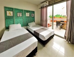 a bedroom with two beds and a balcony with a table at Backpackers And Travellers Art Hostel, Tours Agency huila y colombia in Neiva