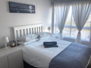 a bedroom with a large white bed and a window at Portico 606 in Bloubergstrand