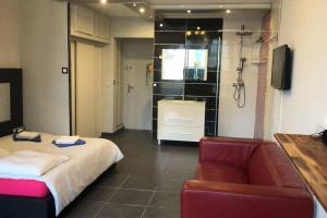 a room with a bed and a chair and a shower at Studio Village Naturiste vue mer HELIOPOLIS C in Cap d'Agde