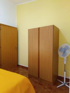 Piccolo Hotel Nuova gestione في كالا غونوني: غرفة نوم بسرير وخزانات خشبية ومروحة