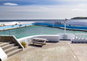 a picnic table in the water next to a beach at Pebbles Marazion in Marazion