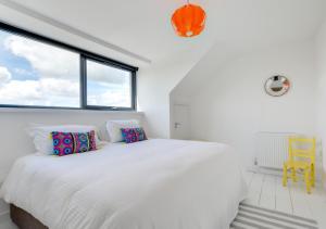 a white bedroom with a large bed and a window at Pen Y Mor in Mawgan Porth