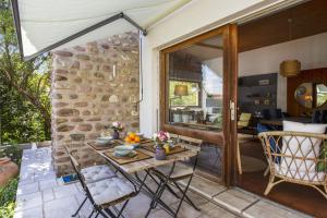 um pátio com uma mesa e cadeiras ao lado de uma parede de pedra em Luminous house nearby the beach - Anglet - Welkeys em Anglet