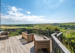 a wooden deck with benches and a view of the countryside at Pen Y Mor in Mawgan Porth